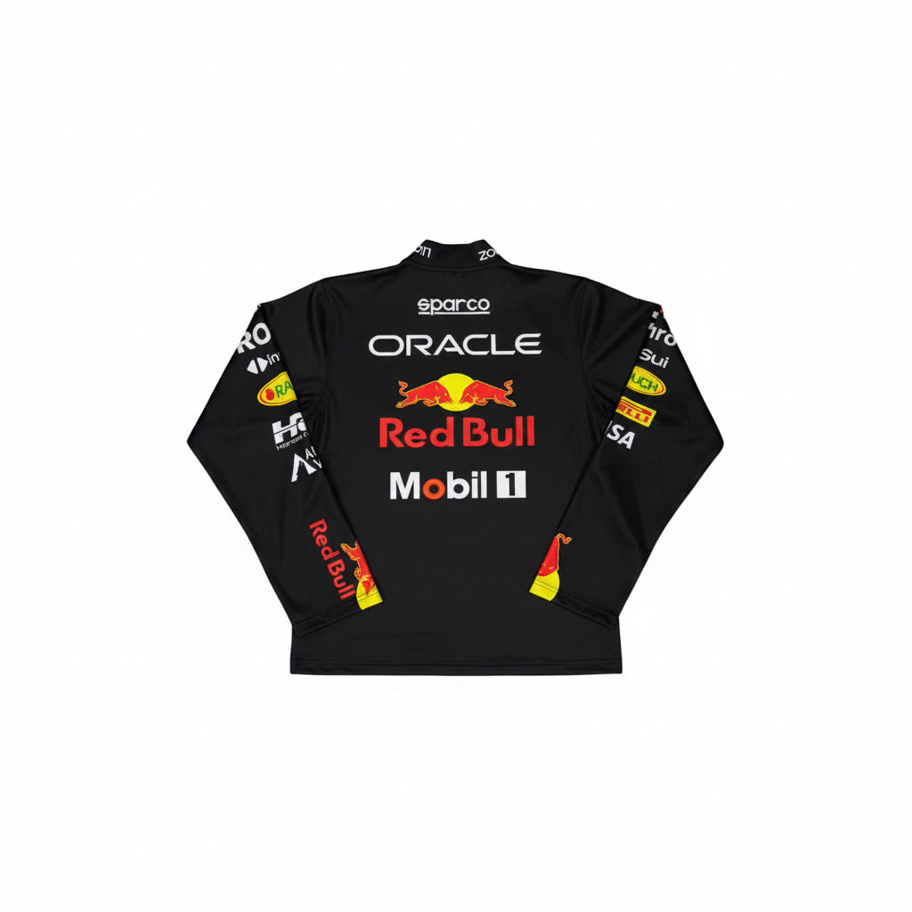 A black long-sleeve Oracle Red Bull Racing team shirt with sponsor logos, laid flat on a gray marble tile floor. The shirt features the Red Bull logo and names including Sparco, Oracle, Mobil 1, and Shell on the front and sleeves.