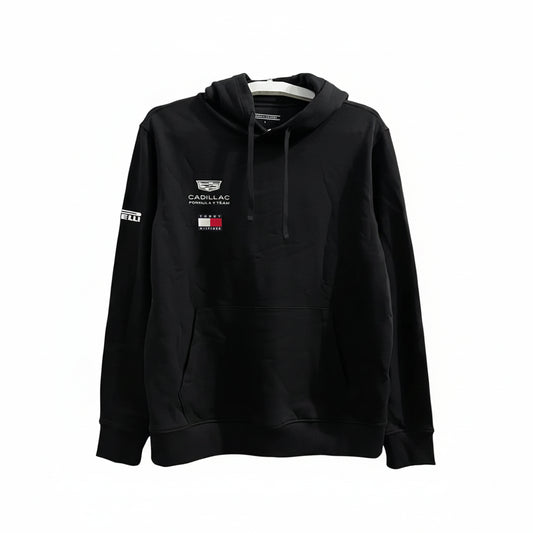 A black pullover hoodie featuring Cadillac F1 Team branding on the left chest and Pirelli on the right sleeve, hanging against a white decorative screen.