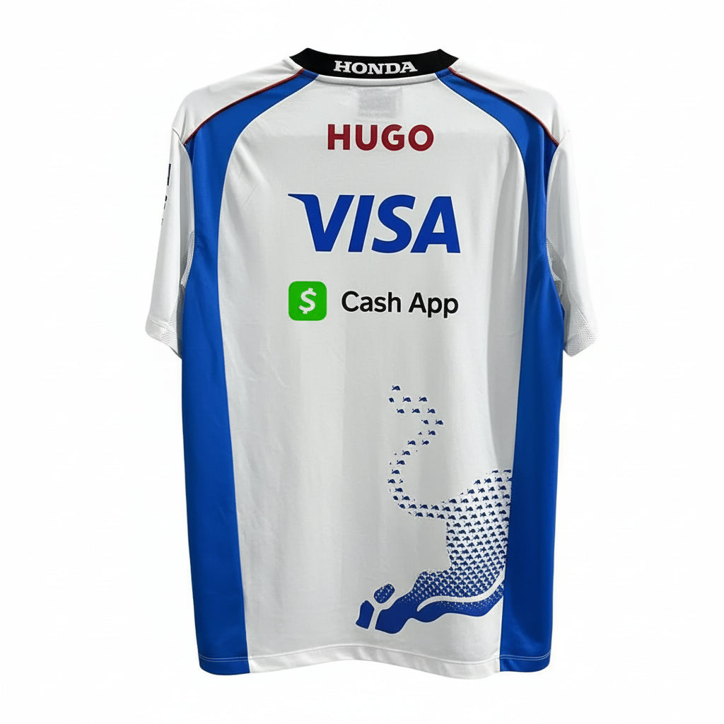 A white and blue short-sleeve sports jersey displayed against a decorative black-and-white geometric wall. The jersey features sponsor logos including HUGO, VISA, Cash App, Honda, Red Bull, XM4TS, and Valyde.