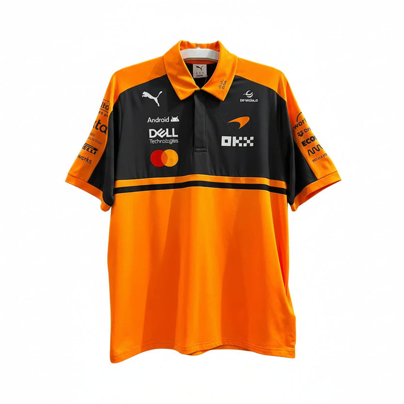 A short-sleeve polo shirt in bright orange and black, featuring sponsor logos including Puma, Dell Technologies, Mastercard, and OKX, displayed against a decorative white leaf-patterned background.