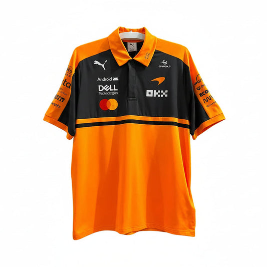 A short-sleeve polo shirt in bright orange and black, featuring sponsor logos including Puma, Dell Technologies, Mastercard, and OKX, displayed against a decorative white leaf-patterned background.