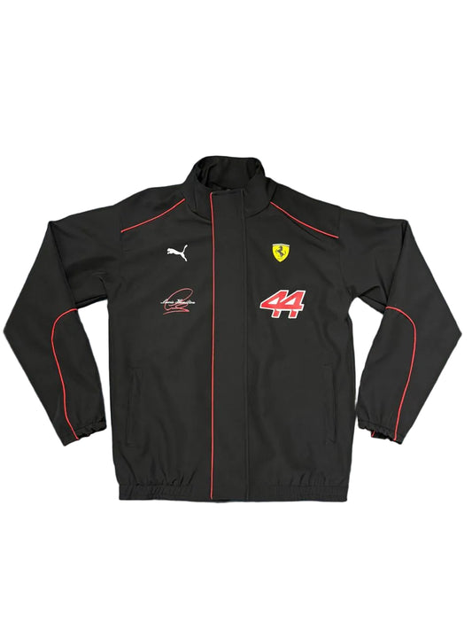 A black Puma Ferrari racing jacket with red piping, the Scuderia Ferrari logo, and the number 44, laid flat on a blue sheet.