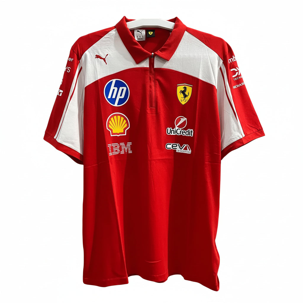 A red and white Scuderia Ferrari short-sleeve polo shirt by Puma, featuring sponsor logos including HP, Shell, Uncredit, and IBM, displayed against a decorative black and white patterned wall.