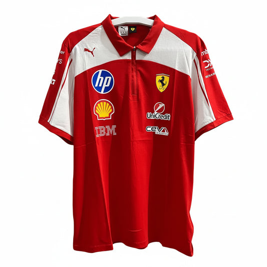 A red and white Scuderia Ferrari short-sleeve polo shirt by Puma, featuring sponsor logos including HP, Shell, Uncredit, and IBM, displayed against a decorative black and white patterned wall.