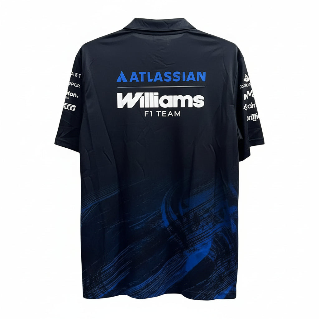 A dark navy blue short-sleeve athletic jersey with 'ATLASSIAN Williams F1 TEAM' printed on the back, displayed on a hanger against a white decorative leaf-patterned wall.