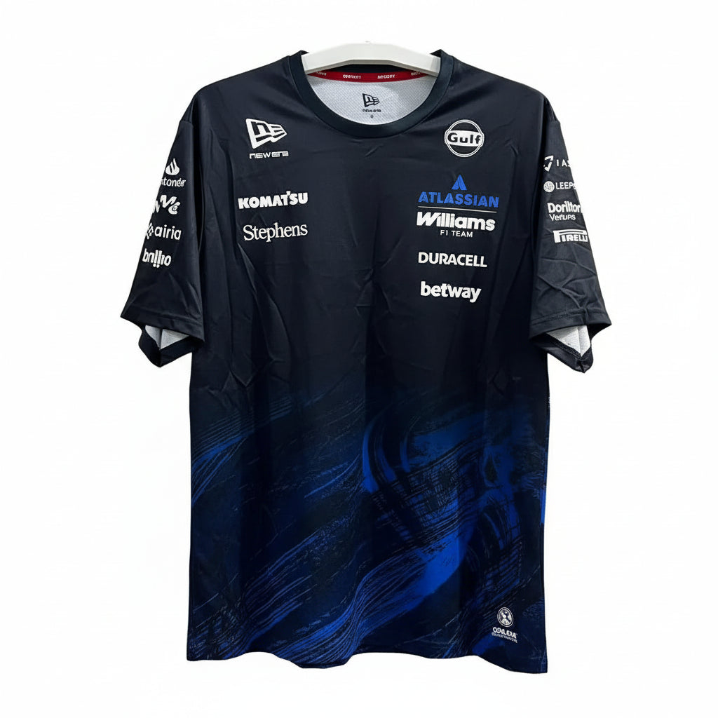 A dark navy blue New Era esports t-shirt with blue graphic patterns and multiple sponsor logos, hanging on a white hanger against a white geometric patterned wall.